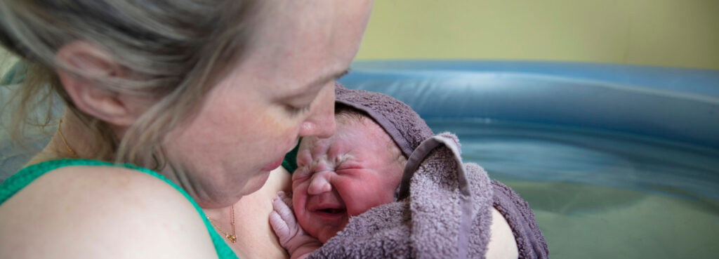 Mutter mit Neugeborenem im Geburtspool