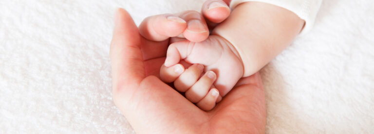 Babyhand in der schützenden Hand von Mama
